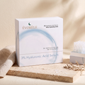 Évorèle HA Glass-Skin Ampoule Vials — white carton with icy-blue water ring, full label visible, tray of vials on travertine